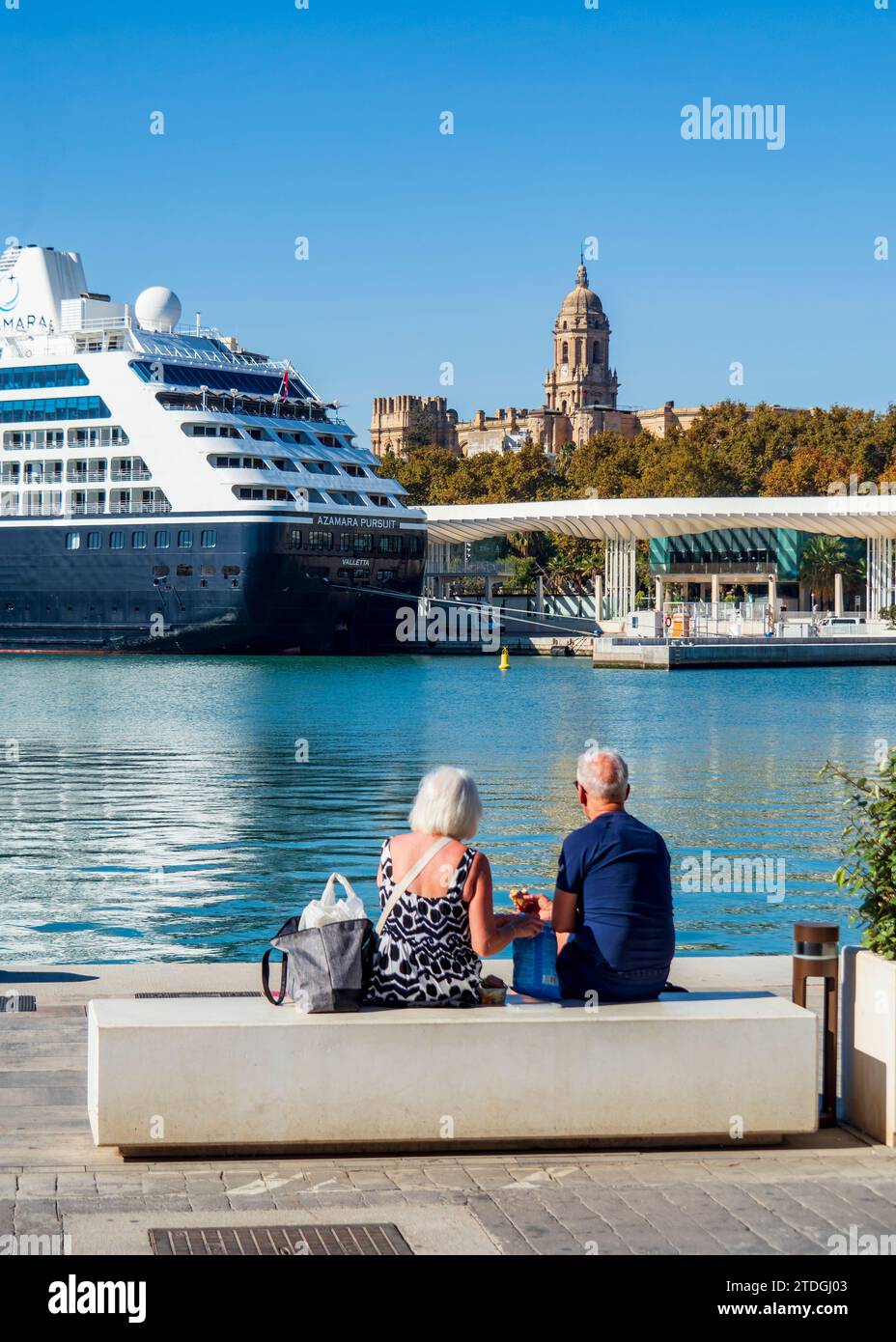 Retired couple in front of pier one of the port of Malaga with the cathedral in the background. Stock Photo