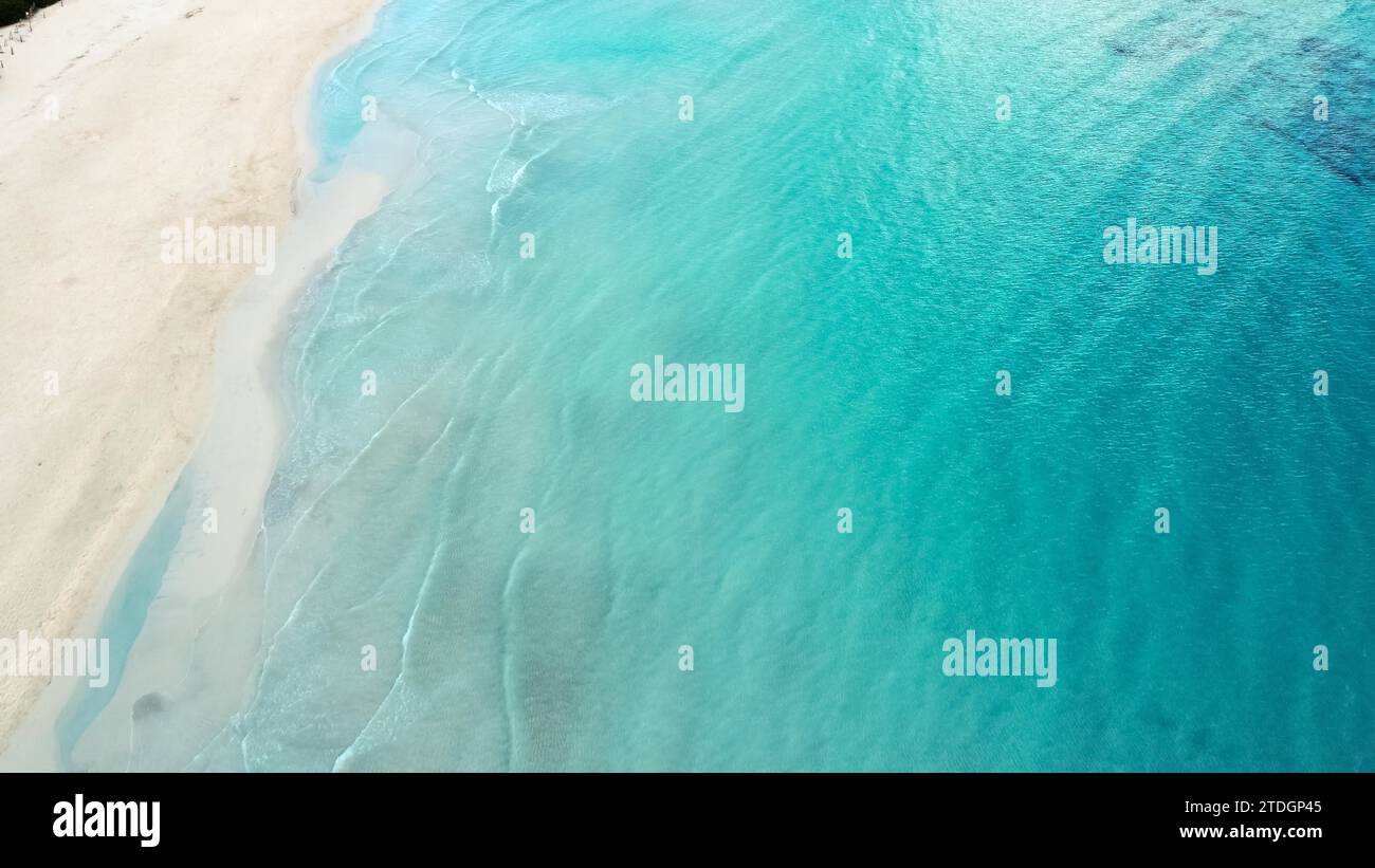Aerial shot of a serene turquoise ocean gently lapping onto a sandy beach Stock Photo