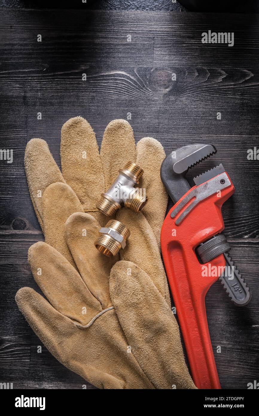 Adjustable wrench plumbing fittings leather safety gloves on wood board Stock Photo