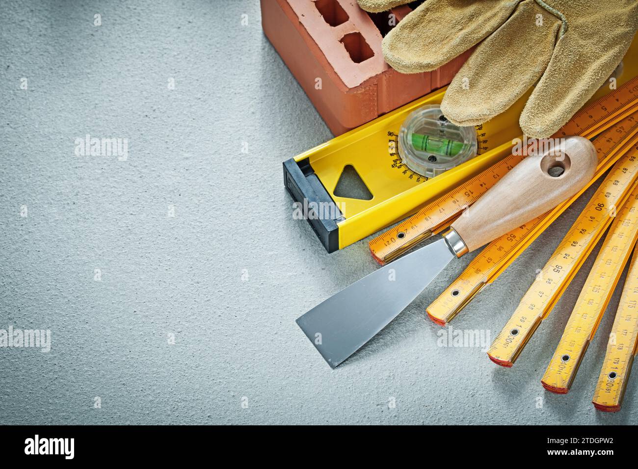 Red brick working gloves plastering trowel construction level wooden meter on concrete background bricklaying concept Stock Photo