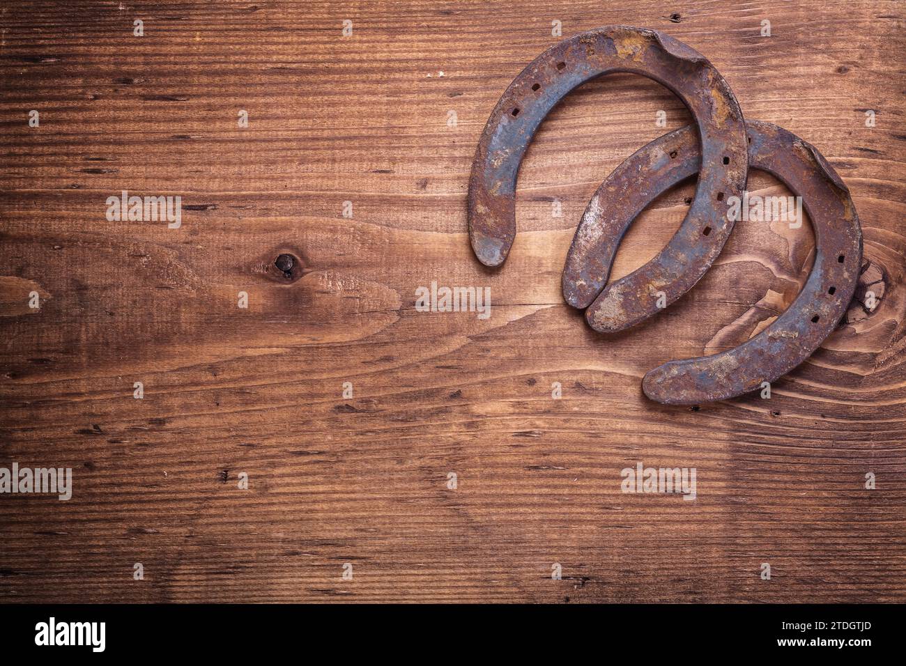 Copyspace image two old cast iron metal western horse shoeing accessories horseshoes on antique wooden background happy concept Stock Photo