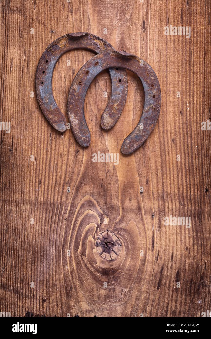 Copyspace image two old cast iron metal western horse shoeing accessory horseshoes on antique wooden background happy concept vertical version Stock Photo