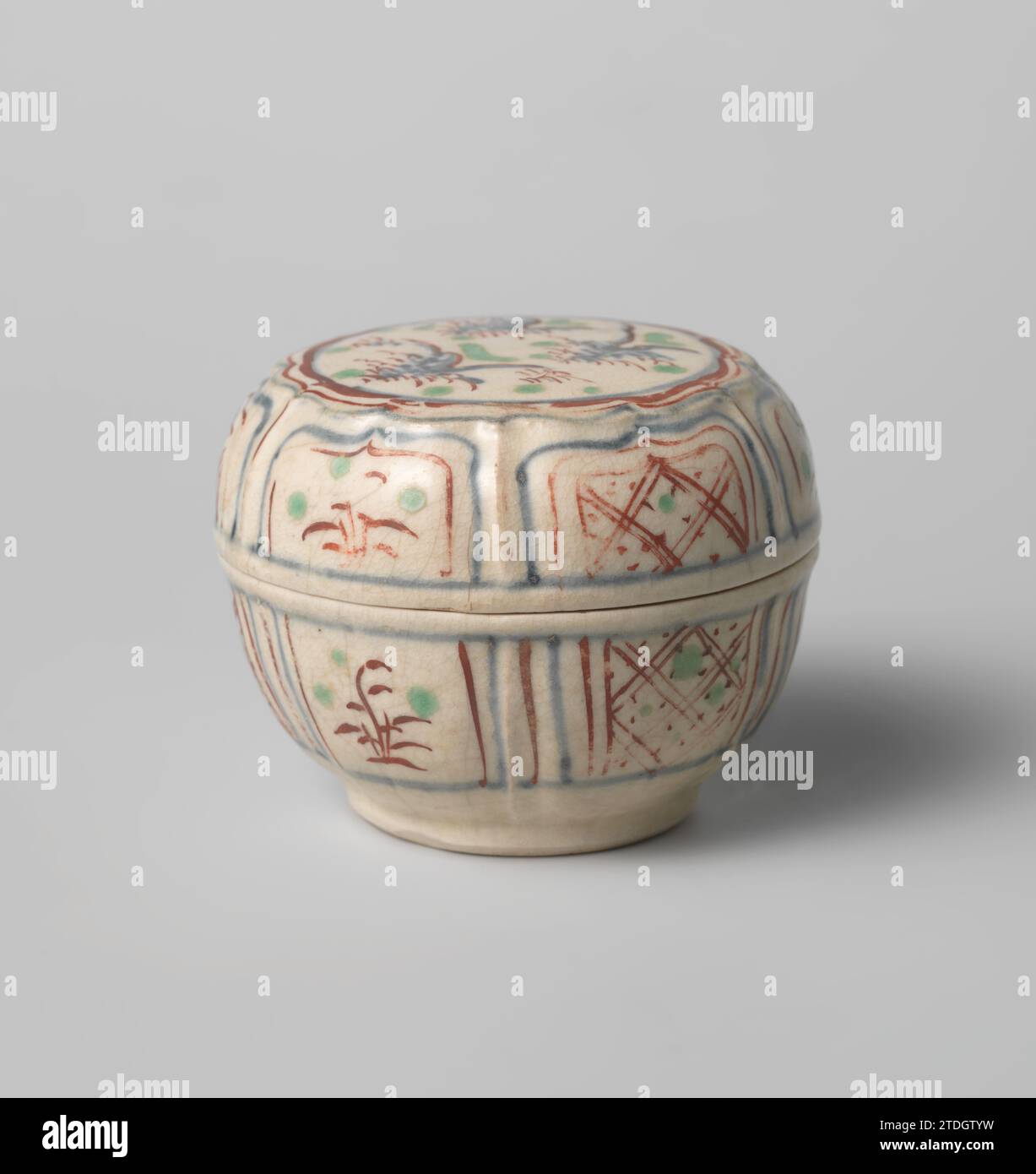 Box with diaper patterns and flowering plants in a panel decoration, anonymous, c. 1400 - c. 1599 Lid of stone box, painted in underly glaze blue and on the glaze red and green. The top of the lid with a modeled, scalloped cartouche with a landscape with mountains and trees. A chip in the edge of the box. Decoration following the Chinese squatter porcelain. Vietnam stoneware. glaze. cobalt (mineral) painting / vitrification Lid of stone box, painted in underly glaze blue and on the glaze red and green. The top of the lid with a modeled, scalloped cartouche with a landscape with mountains and t Stock Photo