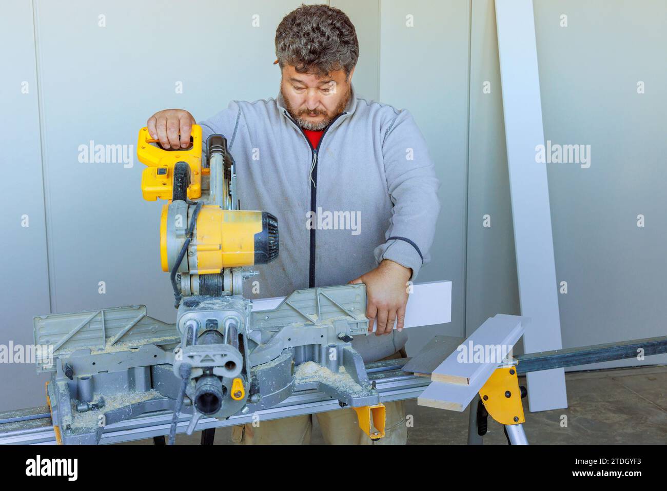 Using chop saw trim worker cuts wood base molding using chop saw Stock