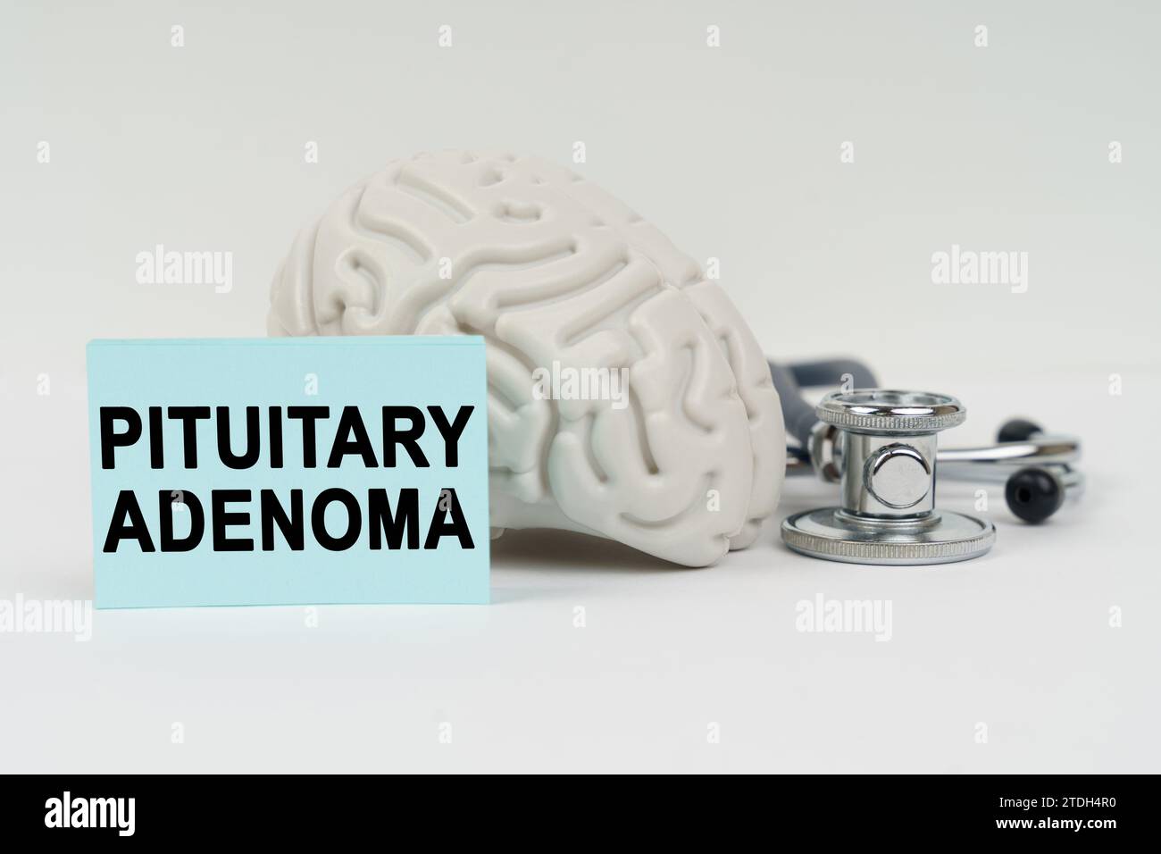 Medical concept. On a white surface next to the brain there is a stethoscope and stickers with the inscription - Pituitary adenoma Stock Photo