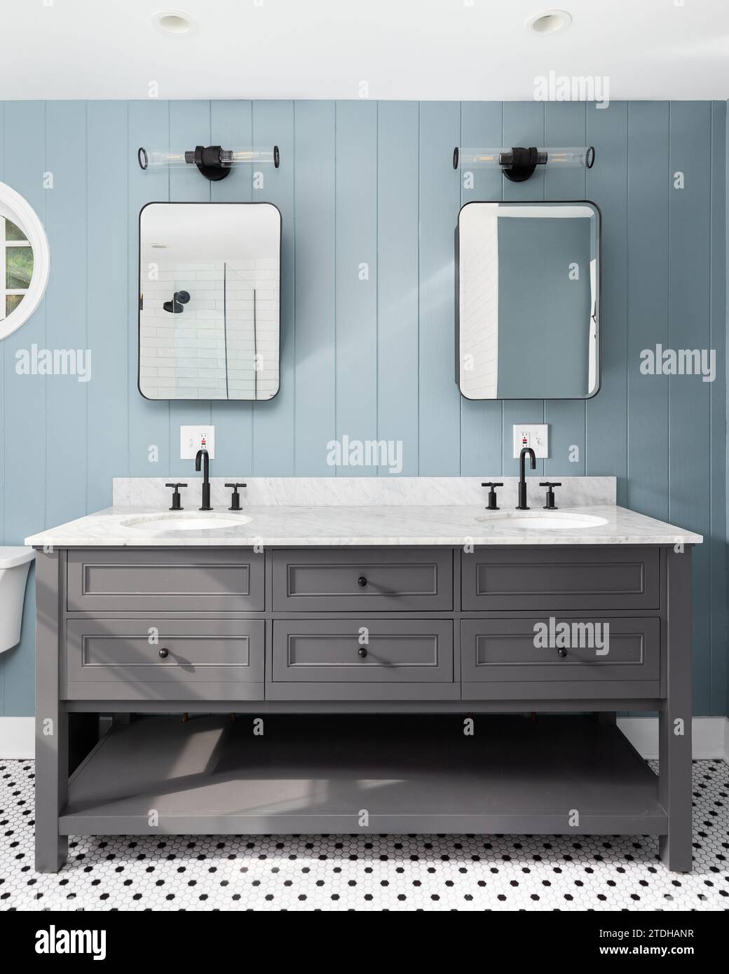 A blue wood panel bathroom with a grey cabinet, white marble countertop ...