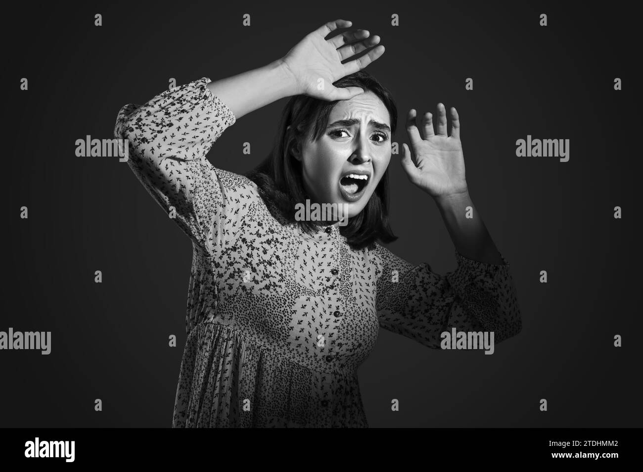 Beautiful young afraid woman screaming on black background Stock Photo