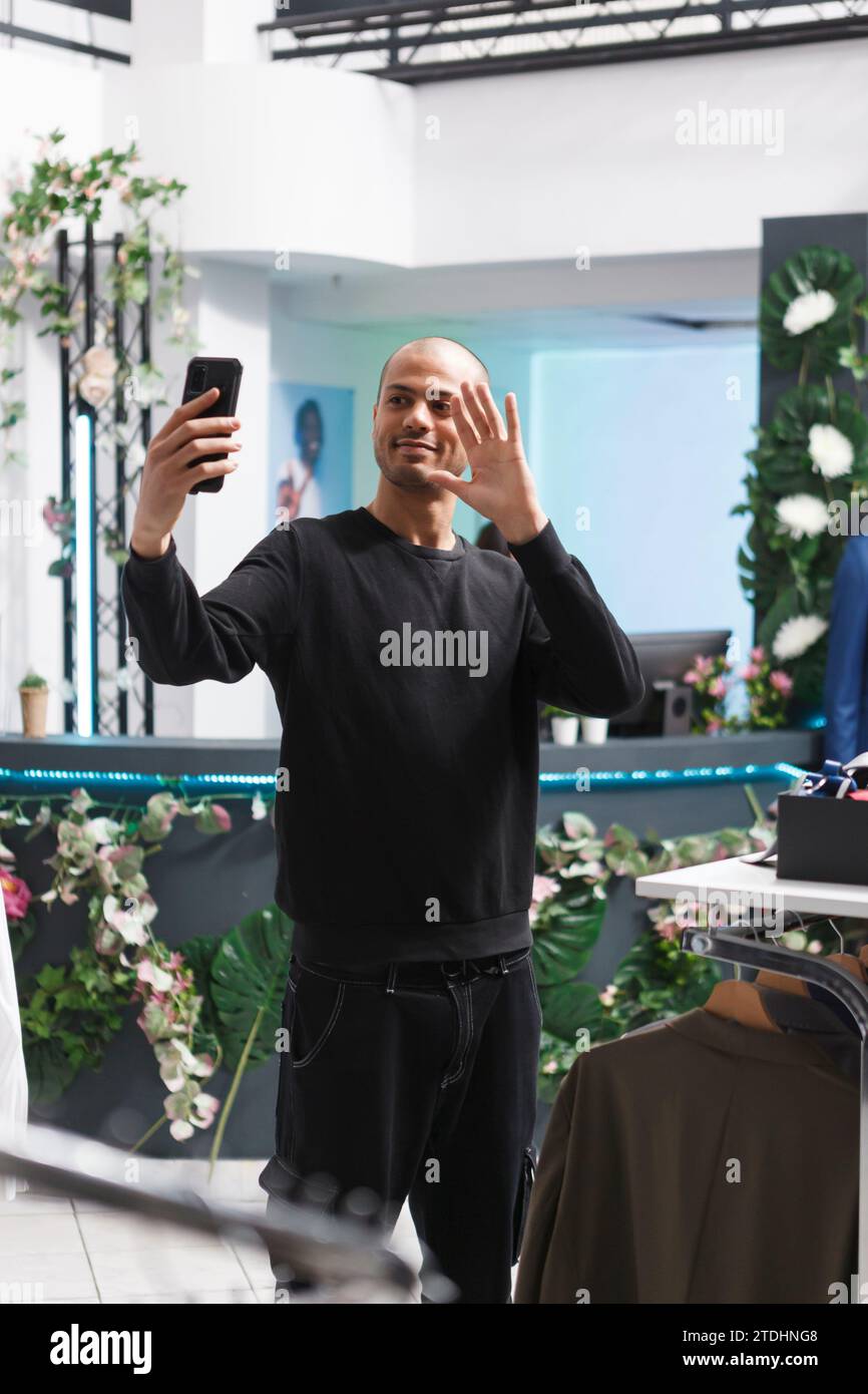 Shopping mall boutique arab man client waving hi while making selfie on ...