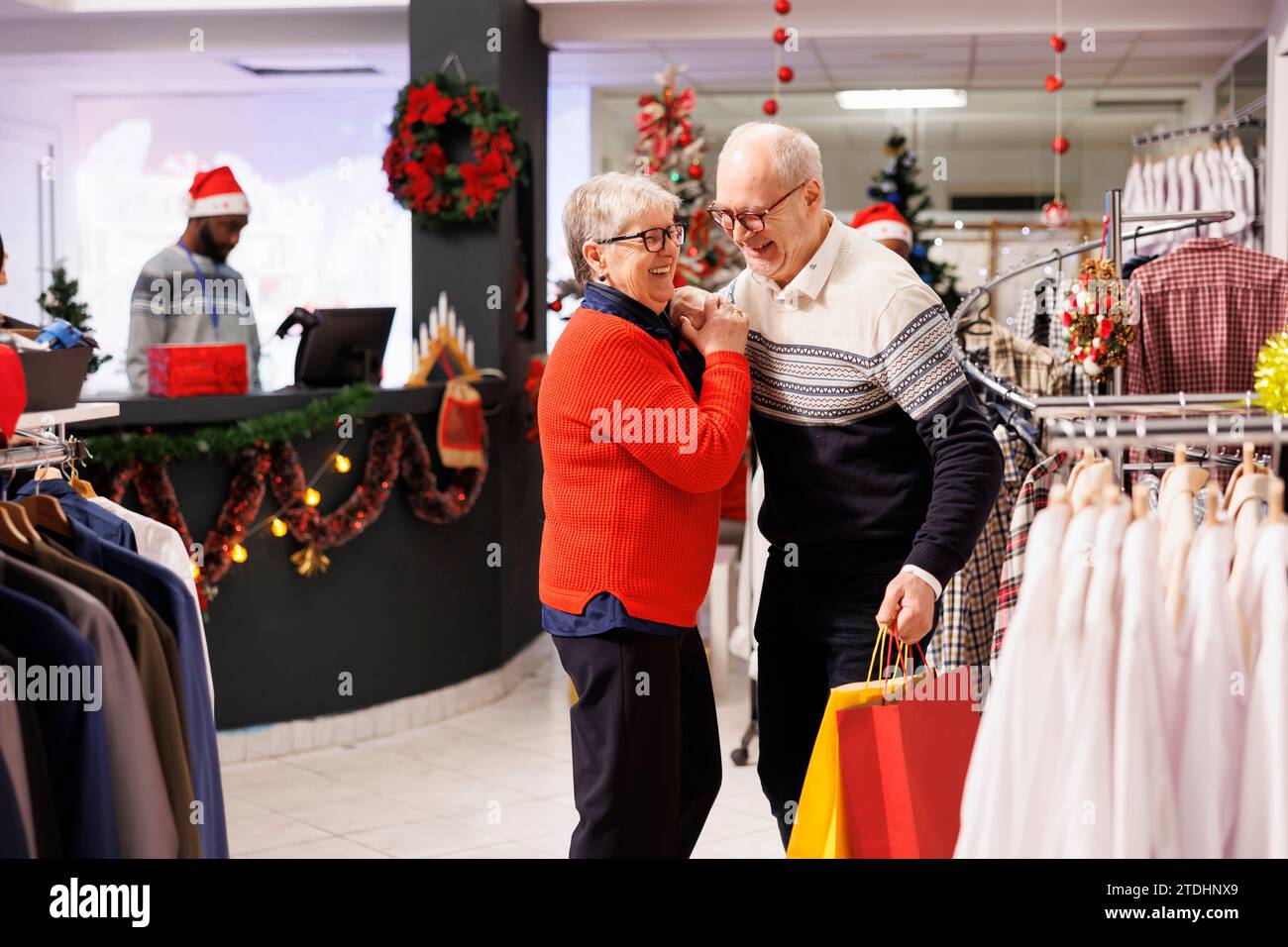 Elderly people doing sweet waltz dance in retail store, showing sincere feelings at mall during seasonal christmas promotions. Romantic man and woman dancing around in shopping center, xmas spirit. Stock Photo