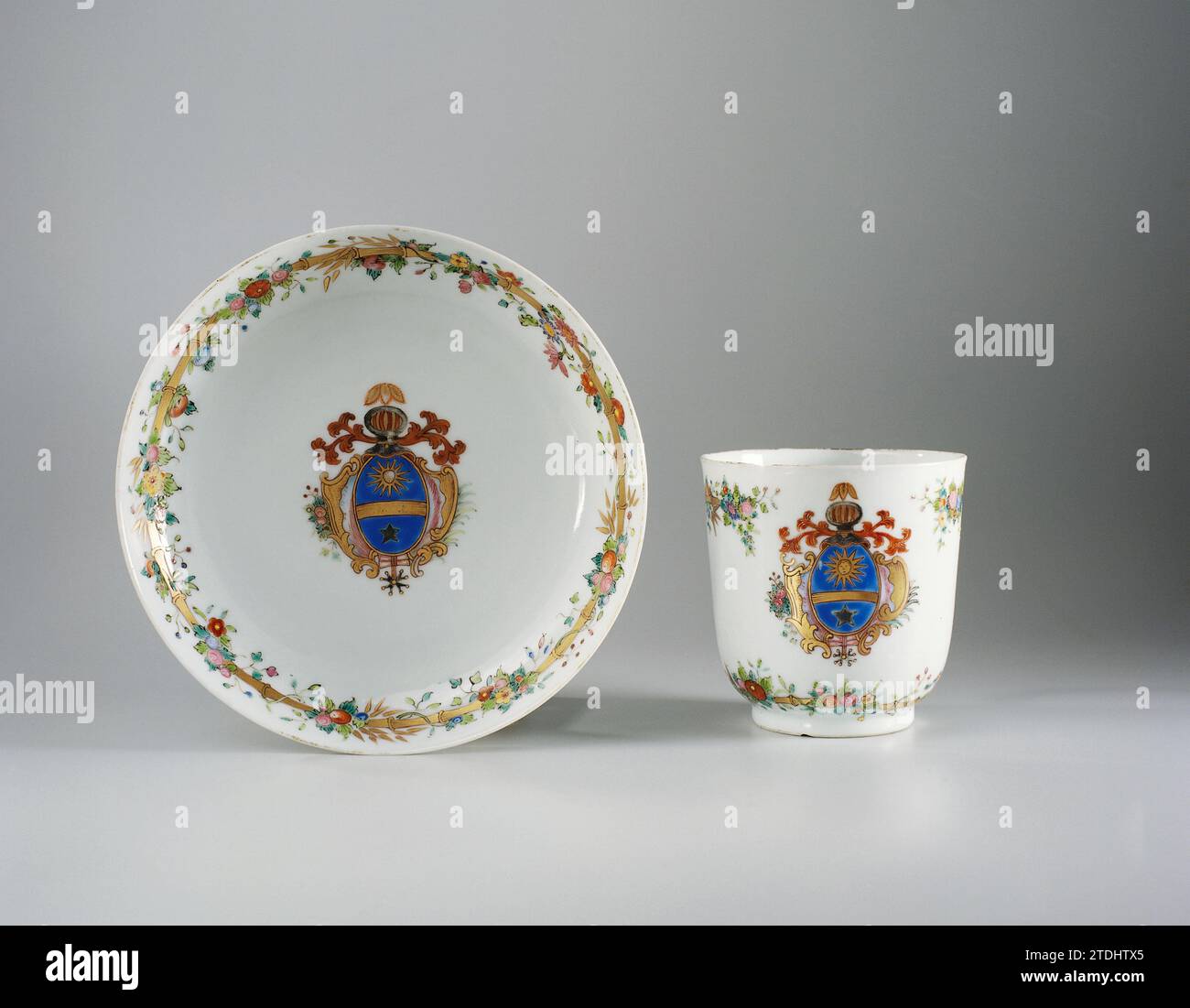 Saucer with a coat of arms and bamboo border with floral scrolls, anonymous, c. 1750 - c. 1774 Porcelain dish, painted on the glaze in blue, red, pink, green, yellow, black and gold. On the flat of the dish an unidentified family crest with a sun with a face, a star and a gold beam on a blue background. The weapon is surrounded by leaf vines, a palm branch and flower branch. On the wall a bamboo band with flower vines. Weapon porcelain with email colors. China porcelain. glaze. gold (metal) painting / gilding / vitrification Porcelain dish, painted on the glaze in blue, red, pink, green, yello Stock Photo