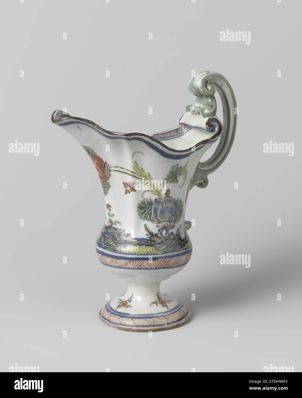 Can, on the abdomen painted with a soil with fence and flower branches, anonymous, c. 1740 - c. 1770 Can of multi -colored flowing. The jug has a corrugated mouth opening with a wide spout and stands on a foot. The belly is half spherical at the bottom and painted with horizontal tires on which a soil with a fence and flower branches. The ear is double C-shaped. Four flower branches were painted on the foot. Italy earthenware. tin glaze. Can of multi -colored flowing. The jug has a corrugated mouth opening with a wide spout and stands on a foot. The belly is half spherical at the bottom and pa Stock Photo