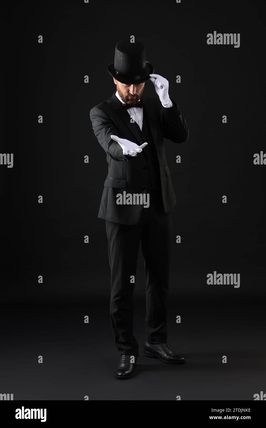 Magician in top hat on black background Stock Photo - Alamy