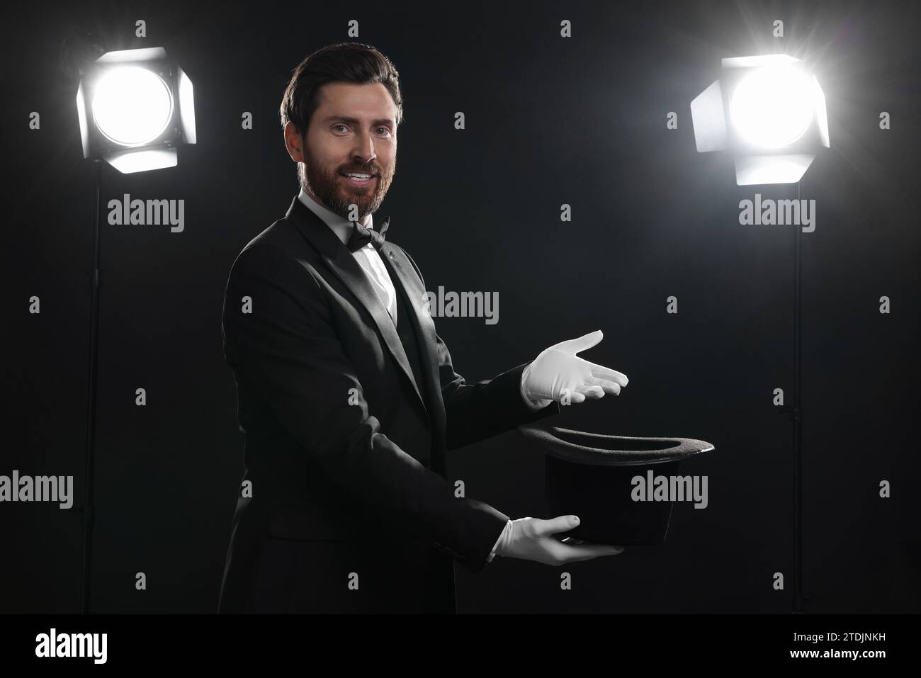 Happy magician holding top hat on stage Stock Photo - Alamy