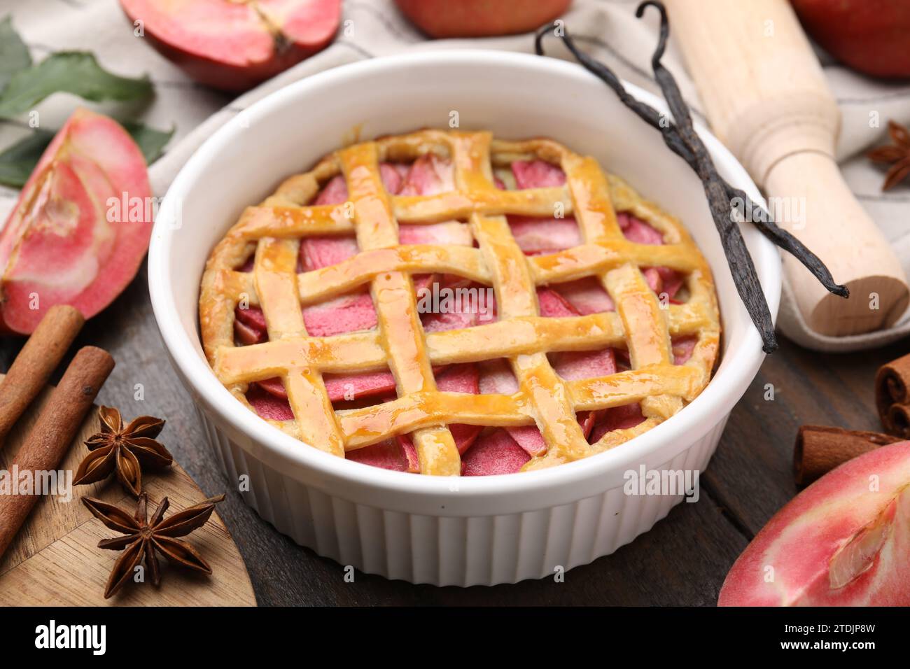 Baking dish with tasty apple pie and spices on wooden table, closeup Stock Photo