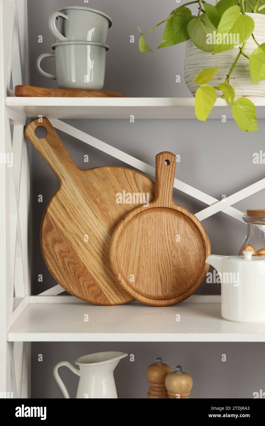 Wooden cutting boards and kitchen utensils on shelving unit Stock Photo