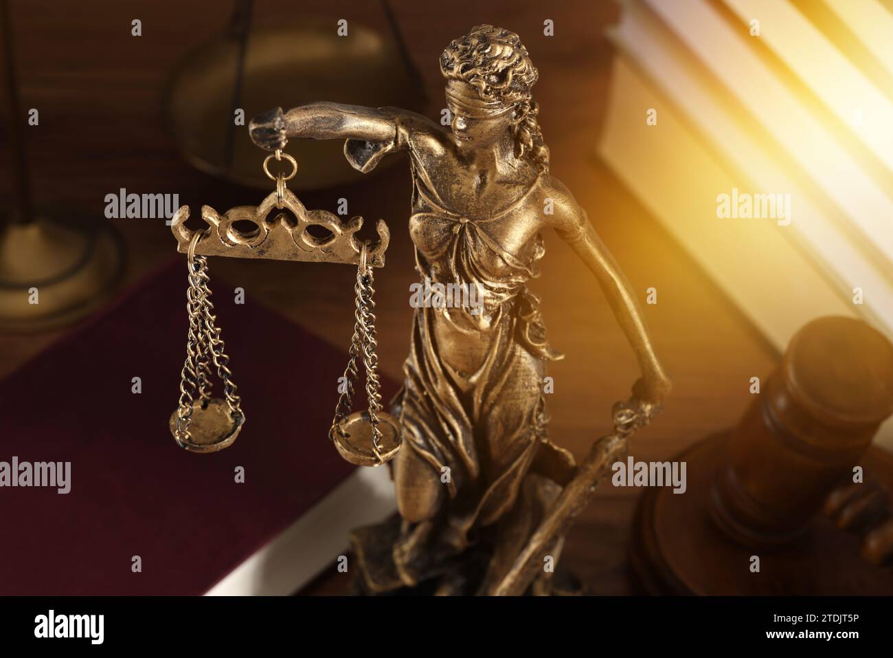 Symbol of fair treatment under law. Statue of Lady Justice, books and gavel on wooden table, closeup Stock Photo