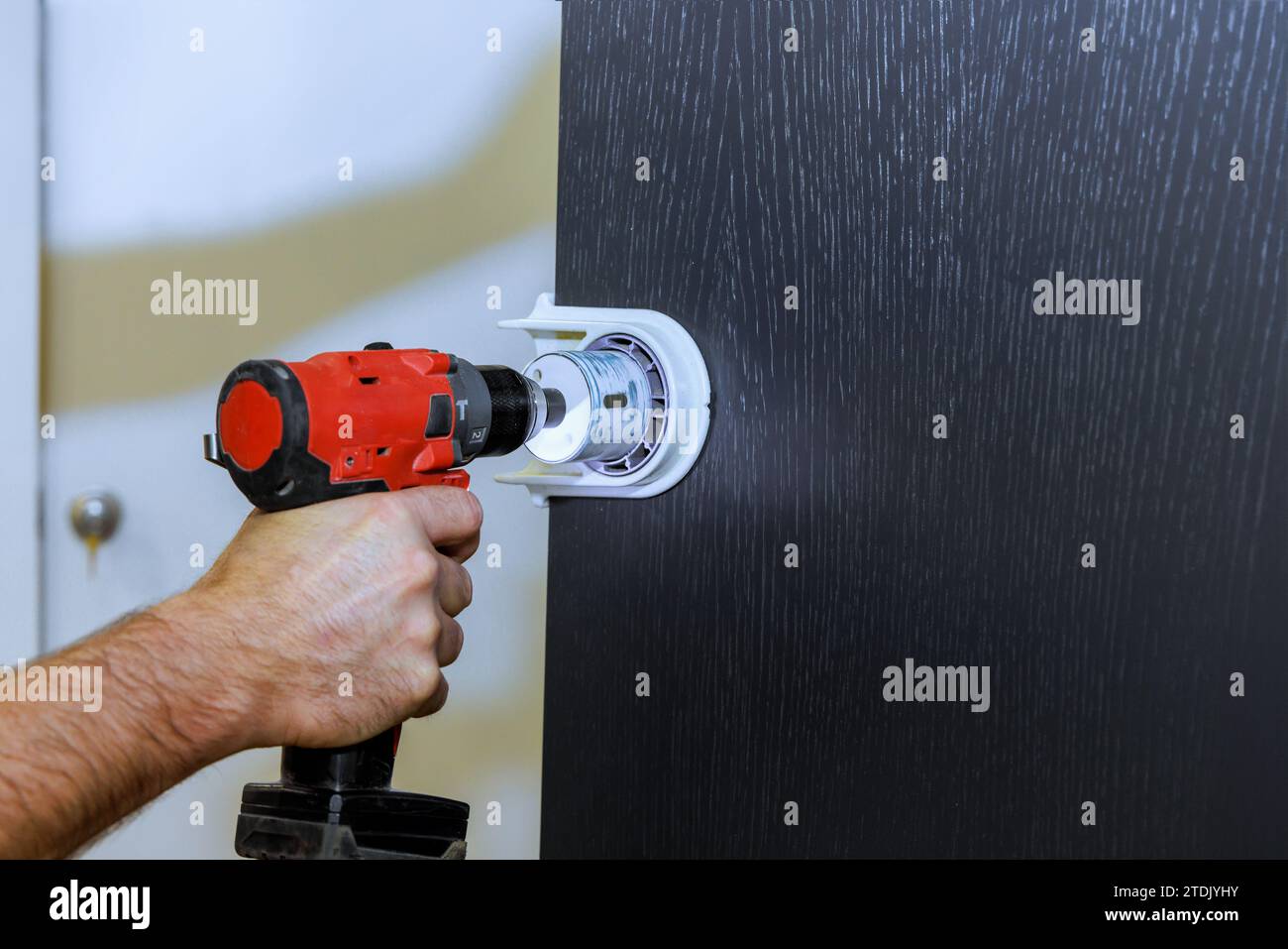 Drilling holes for lock handles in wooden doors by handyman Stock Photo