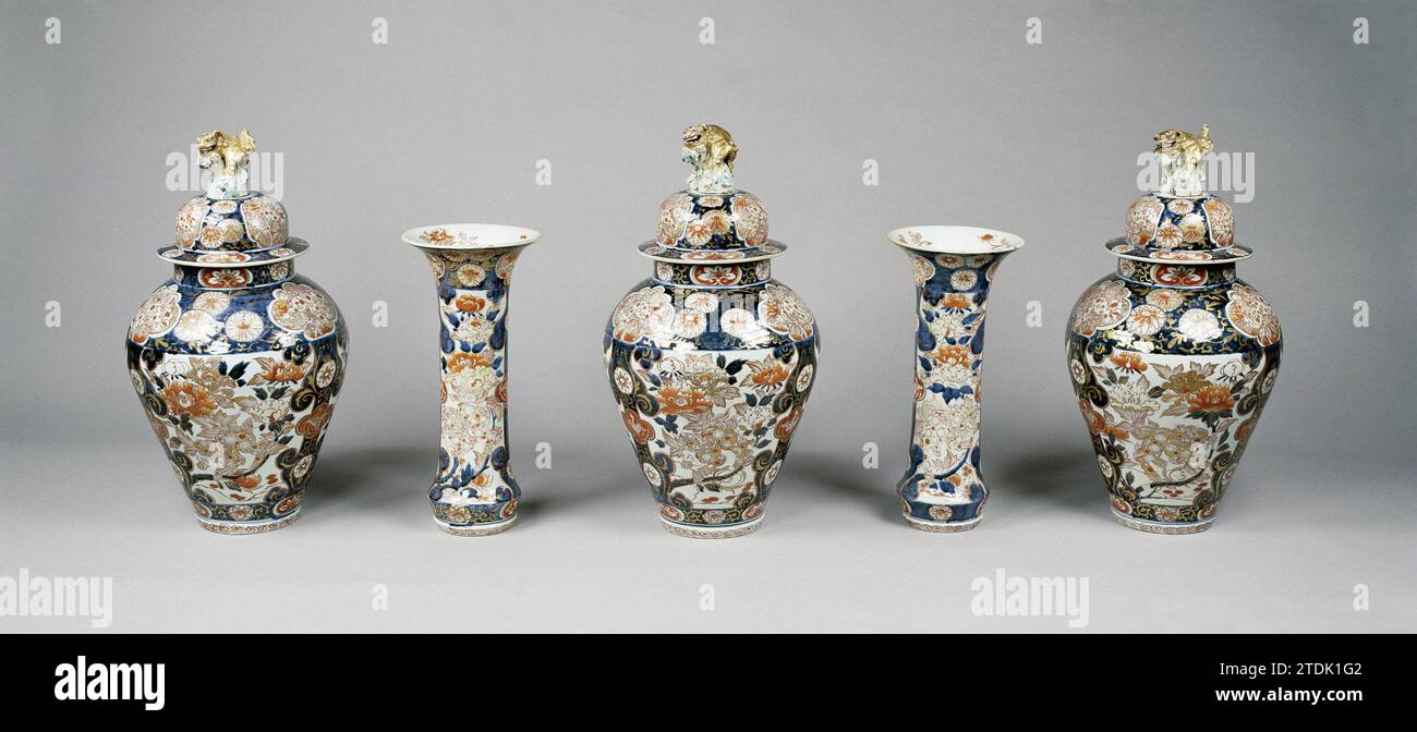 Covered jar with shishi, hoo-birds, flowering plants and floral scrolls, anonymous, c. 1775 - c. 1824 Cabinet of porcelain with three lid pots and two cups, painted in underlaze blue and on the glaze red, black and gold. On the wall three large cartouches with a shishi between a flowering pair of peoning plant; The cartouches are separated by tires of curls containing a lobed cartouche with a Hoo-Vogel surrounded by flower vines. Furthermore, a broad bond with chrysanthemums interrupted by lobed cartouches with a shishi near a plant and a bond with lotus drinks. A band with curl work on the fo Stock Photo