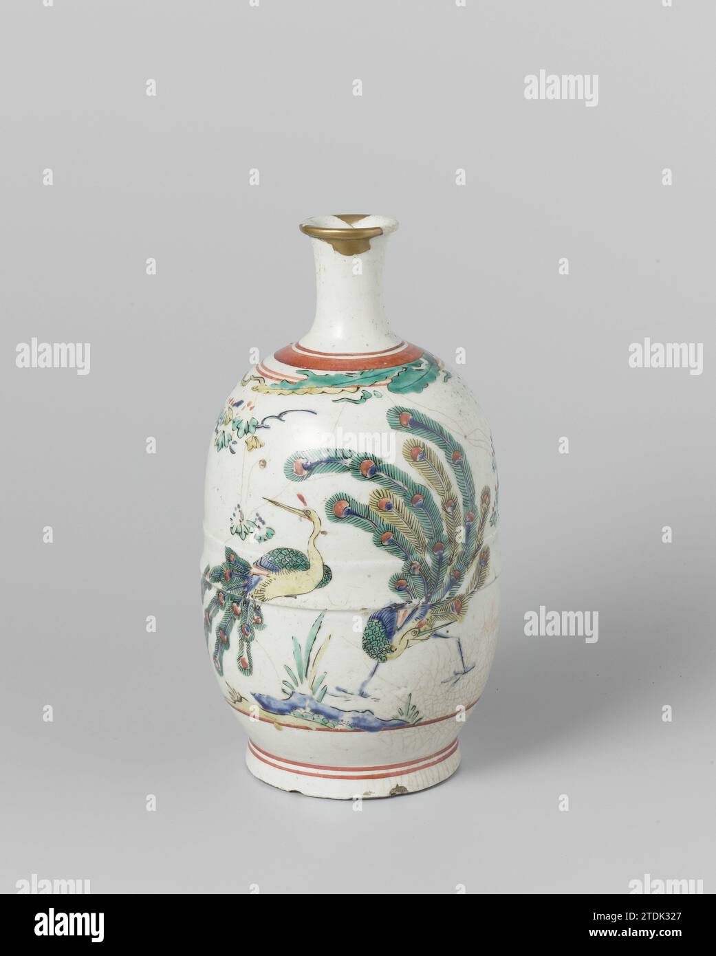Sake bottle with two peacocks near a rock with a flowering plant, anonymous, c. 1660 - c. 1680 Bottle (sake bottle) of porcelain with a narrow, slightly spreading neck, painted on the glaze in blue, red, green, yellow and black. On the abdomen twice a peacock with a rock with a flowering plant. Leaves and red lines on the shoulder. Gold paint repair in the edge. Arita (Kakiemon style). Japan porcelain. glaze. painting / vitrification Bottle (sake bottle) of porcelain with a narrow, slightly spreading neck, painted on the glaze in blue, red, green, yellow and black. On the abdomen twice a peaco Stock Photo