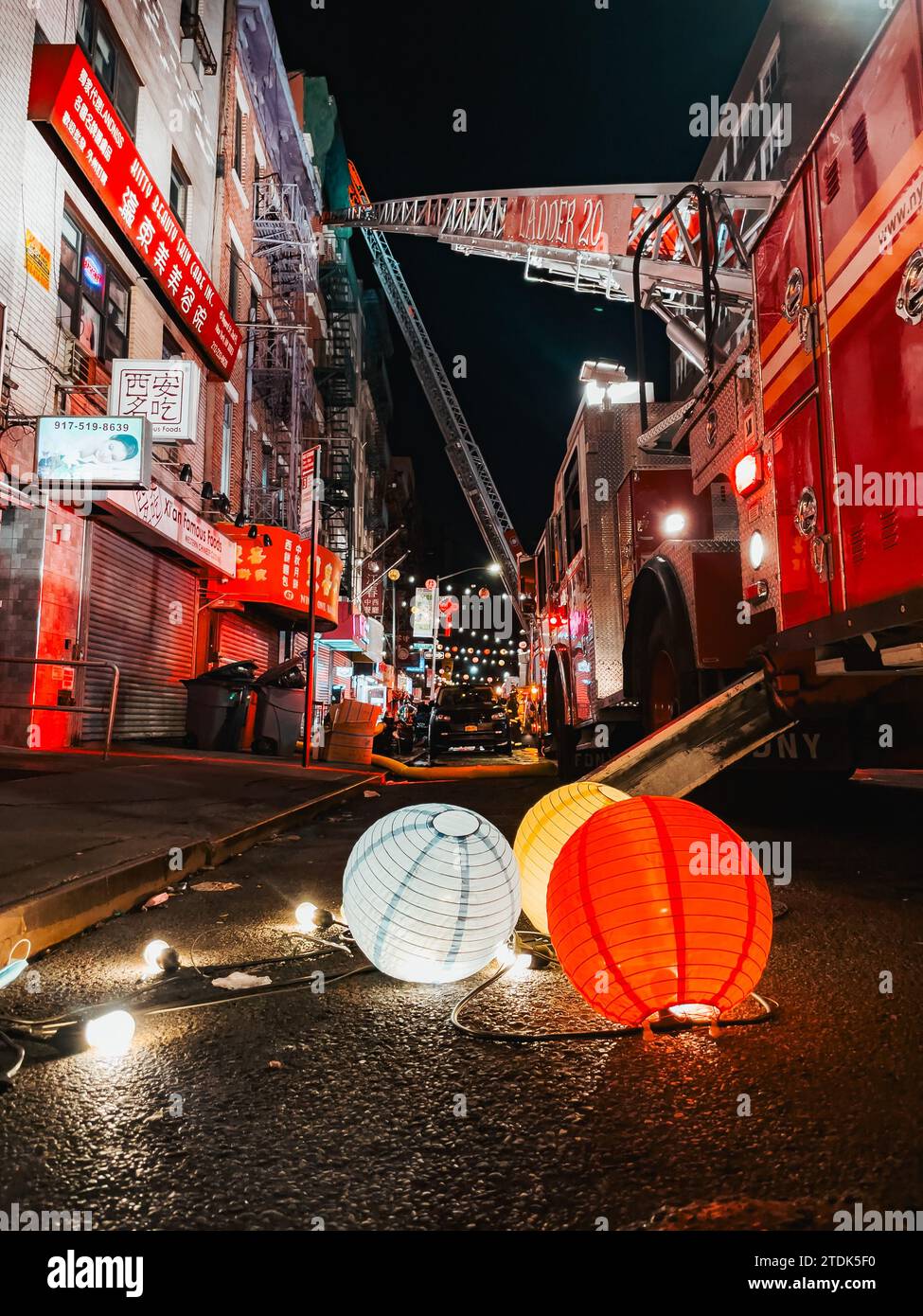 Chinese lanterns lay on the ground in Chinatown, NYC, after being removed to allow a FDNY truck to extend its ladder while fighting a fire Stock Photo