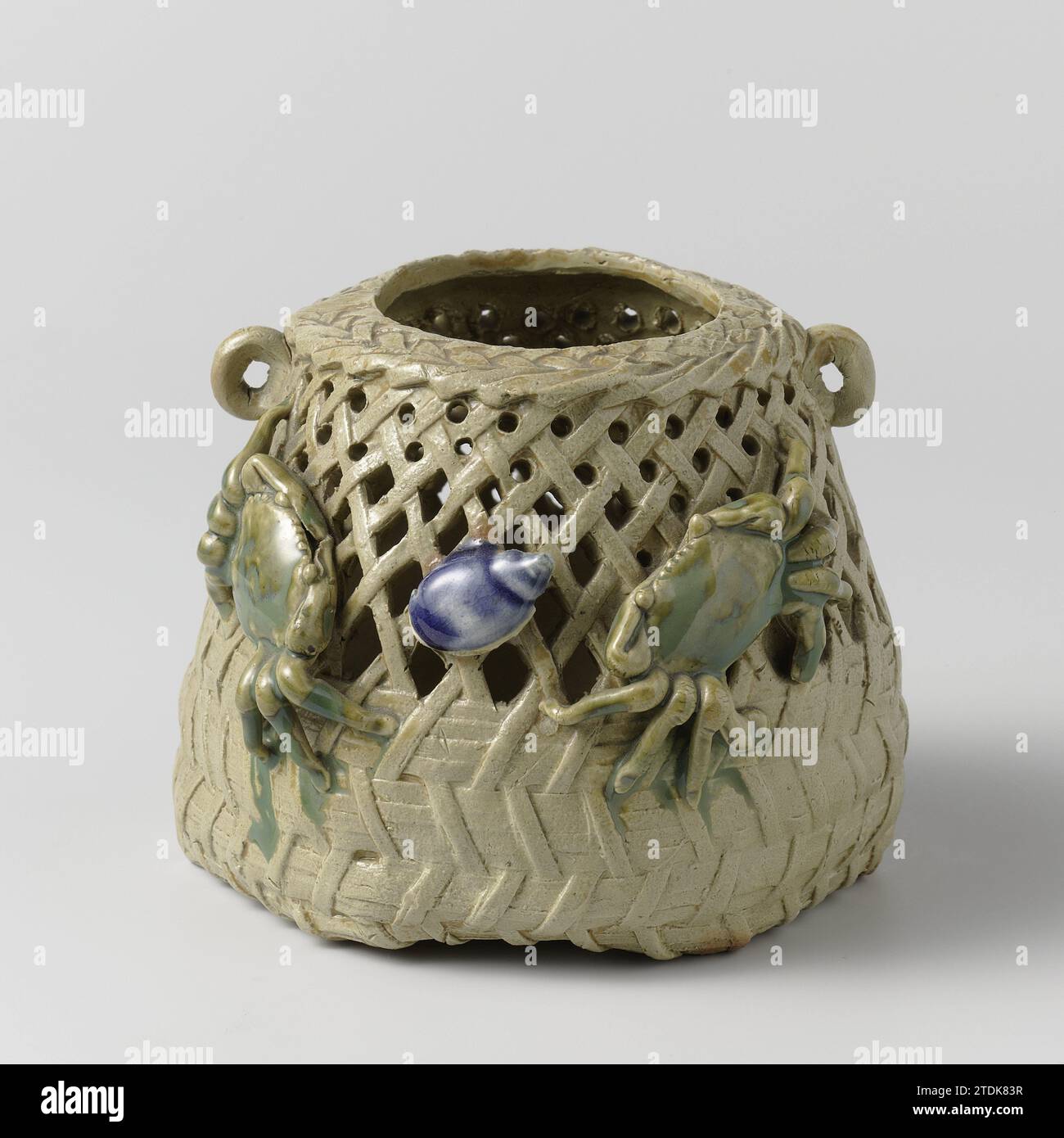 Pierced jar in the shape of a basket with two crabs and a conch, anonymous, c. 1875 - c. 1899 Pot of stoneware in the form of a basket with openwork wall and two small, raised ears, painted on the glaze in blue and green. Two modeled scratches and a shell on the outside wall. Six holes in the soil. Japan stoneware. glaze. vitrification Pot of stoneware in the form of a basket with openwork wall and two small, raised ears, painted on the glaze in blue and green. Two modeled scratches and a shell on the outside wall. Six holes in the soil. Japan stoneware. glaze. vitrification Stock Photo