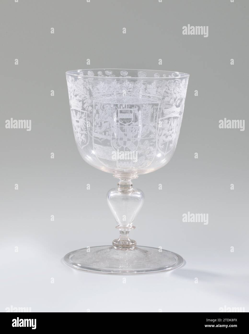 Wine glass, anonymous, c. 1675 - c. 1700 Flat base with turned around and pontil brand. Hollow, baluster -shaped trunk with two discs. Light Konian, rounded chalice at the bottom. On the chalice, the crowned weapon of Stadholder Prince William III is engraved and the crowned weapons of the seven provinces under a continuous branch of orange apples. A branch with orange apples and roses on the foot. glassblower: Low CountriesNorthern Netherlands glass glassblowing Flat base with turned around and pontil brand. Hollow, baluster -shaped trunk with two discs. Light Konian, rounded chalice at the b Stock Photo