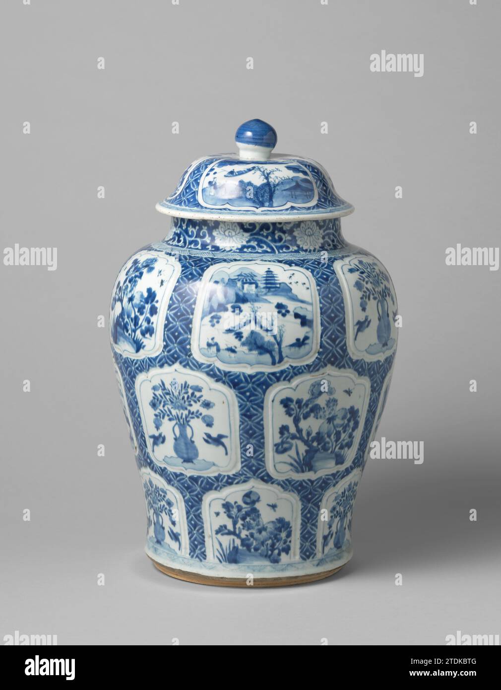 Baluster covered jar with flower vases, flowering plants and landscapes in panels, anonymous, c. 1680 - c. 1720 Balus -shaped porcelain lid jar, painted in underlaze blue. The belly is covered with servetwork with modeled modeled, scalloped cartouches with a flower vase (lotus) with two birds, flowering plants (peony) in a rock or a river landscap with two person, a boat, pavilions, trees and mountains. The neck with stylized lotus drinks. On the shoulder and around the foot a bond with archery. The lid with the same decoration. Blue White. China porcelain. glaze. cobalt (mineral) painting / v Stock Photo