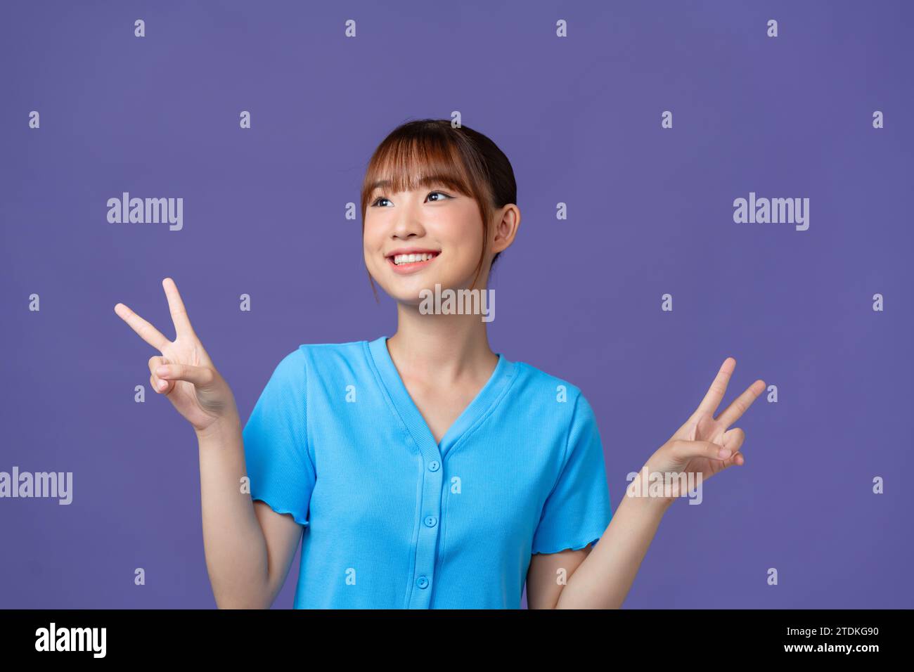 Portrait of funky pretty young person beaming smile finger show v-sign isolated on purple background Stock Photo
