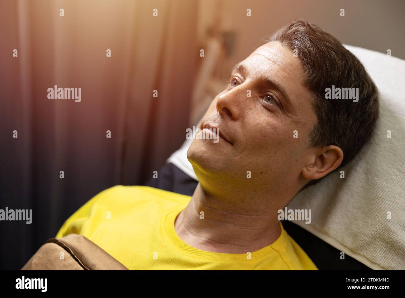 closeup caucasian adult male face head model handsome laying on cosmetic clinic bed relax smile waiting for facial treatment procedure Stock Photo