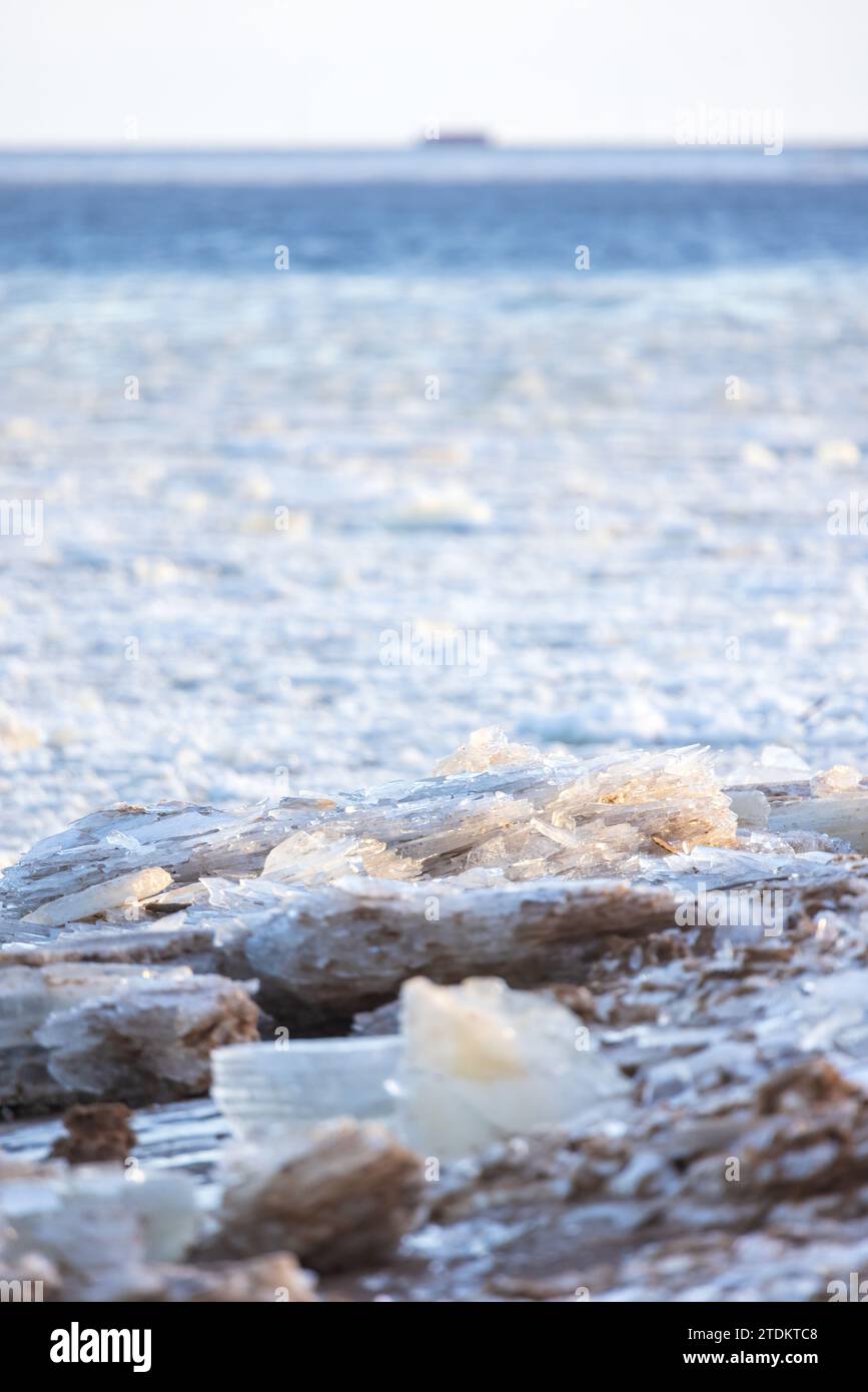 Vertical winter landscape photo with ice shards laying at the coast of frozen Baltic Sea on a winter day, close up view with selective focus Stock Photo