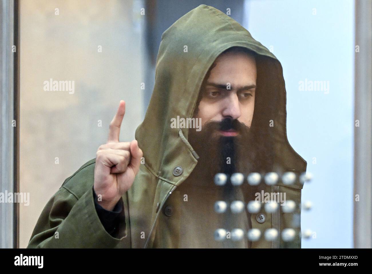 Duesseldorf, Germany. 19th Dec, 2023. The accused Maan D. enters the courtroom at the beginning of the trial for the Duisburg knife attacks and shows the salute of the IS fighters, Tauhid. In the trial for the murderous knife attacks in Duisburg, the confessed Islamist is facing the maximum sentence. The Düsseldorf Higher Regional Court is due to announce the verdict. Credit: Federico Gambarini/dpa/Alamy Live News Stock Photo