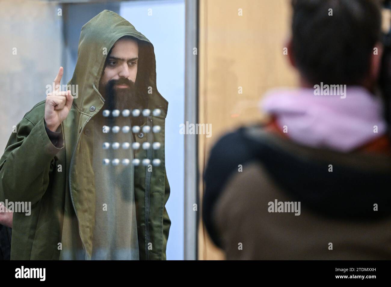 Duesseldorf, Germany. 19th Dec, 2023. The accused Maan D. enters the courtroom at the beginning of the trial for the Duisburg knife attacks and shows the salute of the IS fighters, Tauhid. In the trial for the murderous knife attacks in Duisburg, the confessed Islamist is facing the maximum sentence. The Düsseldorf Higher Regional Court is due to announce the verdict. Credit: Federico Gambarini/dpa/Alamy Live News Stock Photo