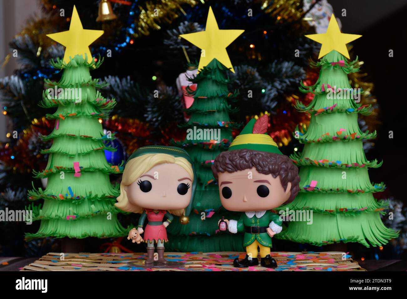 Funko Pop action figures of Jovie and Buddy from family comedy movie Elf. Handmade paper Christmas trees, ornaments, confetti, garland, festive decor. Stock Photo