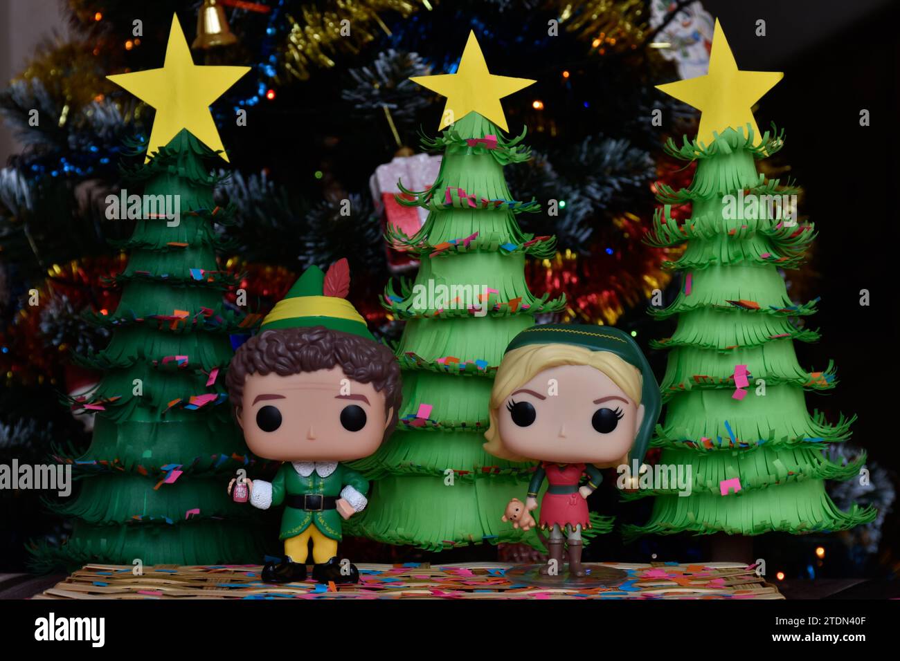 Funko Pop action figures of Buddy and Jovie from family comedy movie Elf. Handmade paper Christmas trees, ornaments, confetti, garland, festive decor. Stock Photo