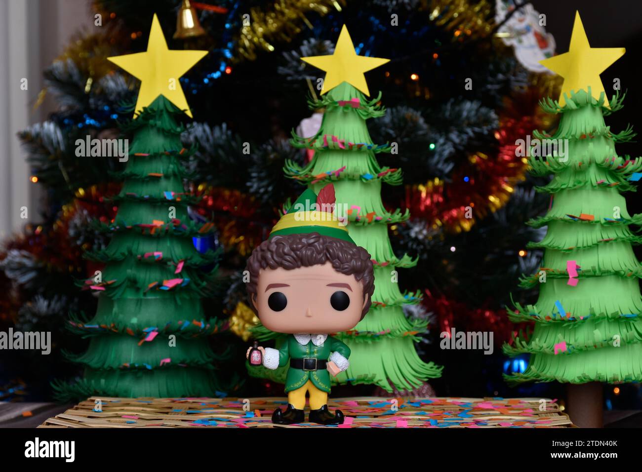 Funko Pop action figure of Buddy from family comedy movie Elf. Handmade paper Christmas trees, ornaments, confetti, garland, festive decor. Stock Photo