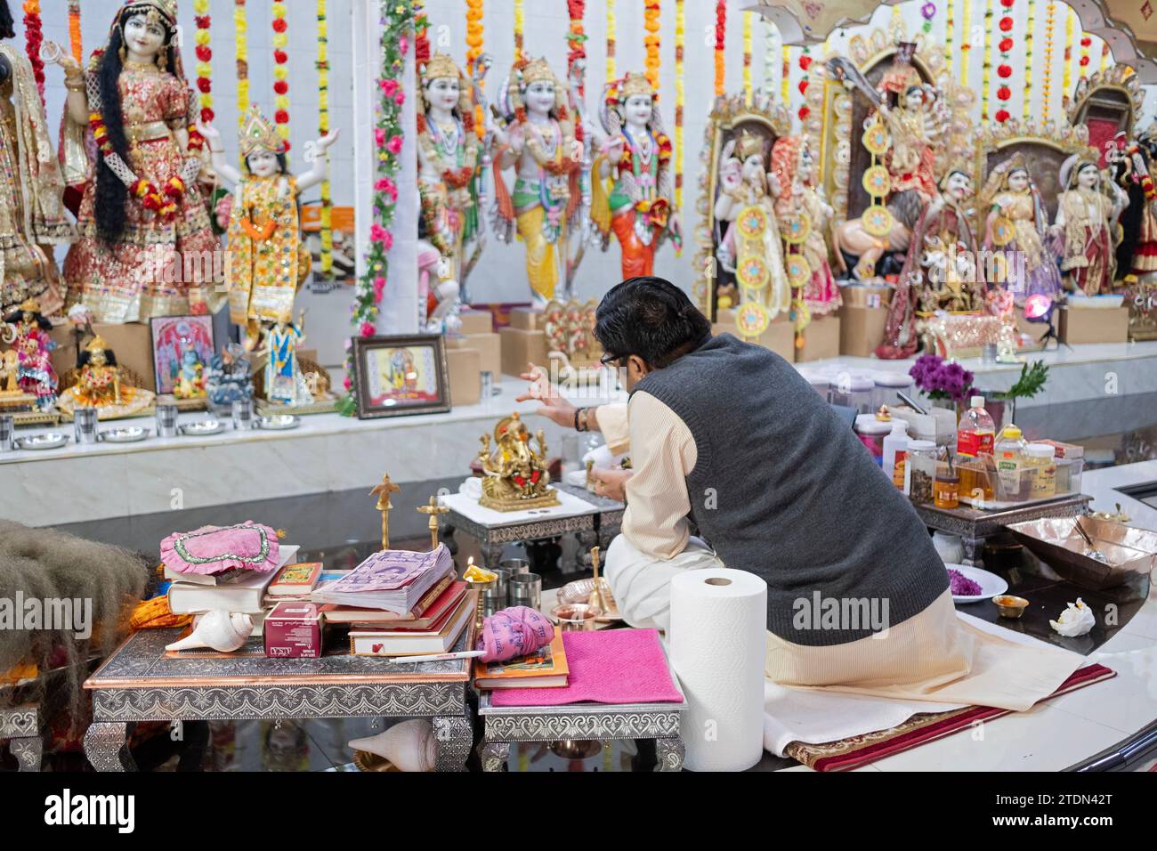 A Hindu priest puts a bindi on a small statue of Ganesh at the Geeta Hindu temple in Corona, Queens, New York City. Stock Photo