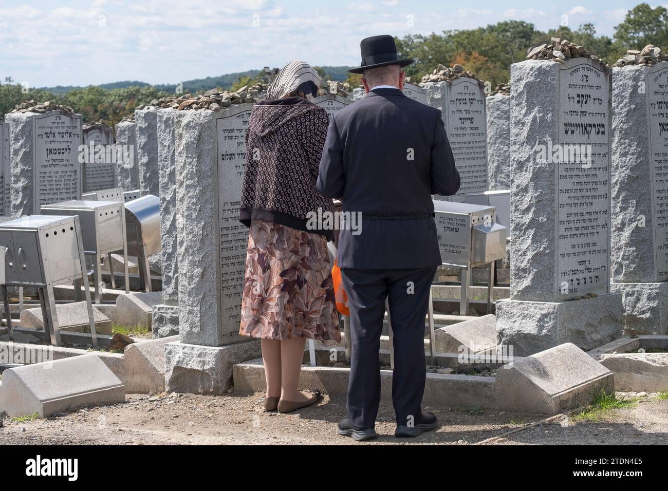 A hasidic couple pray at the headstone of a family member at the Old