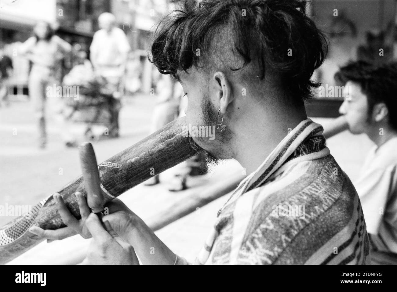 Didgeridoo player in Barteljorisstraat, Haarlem, Barteljorisstraat, The Netherlands, 23-08-1994, Whizgle News from the Past, Tailored for the Future. Explore historical narratives, Dutch The Netherlands agency image with a modern perspective, bridging the gap between yesterday's events and tomorrow's insights. A timeless journey shaping the stories that shape our future Stock Photo