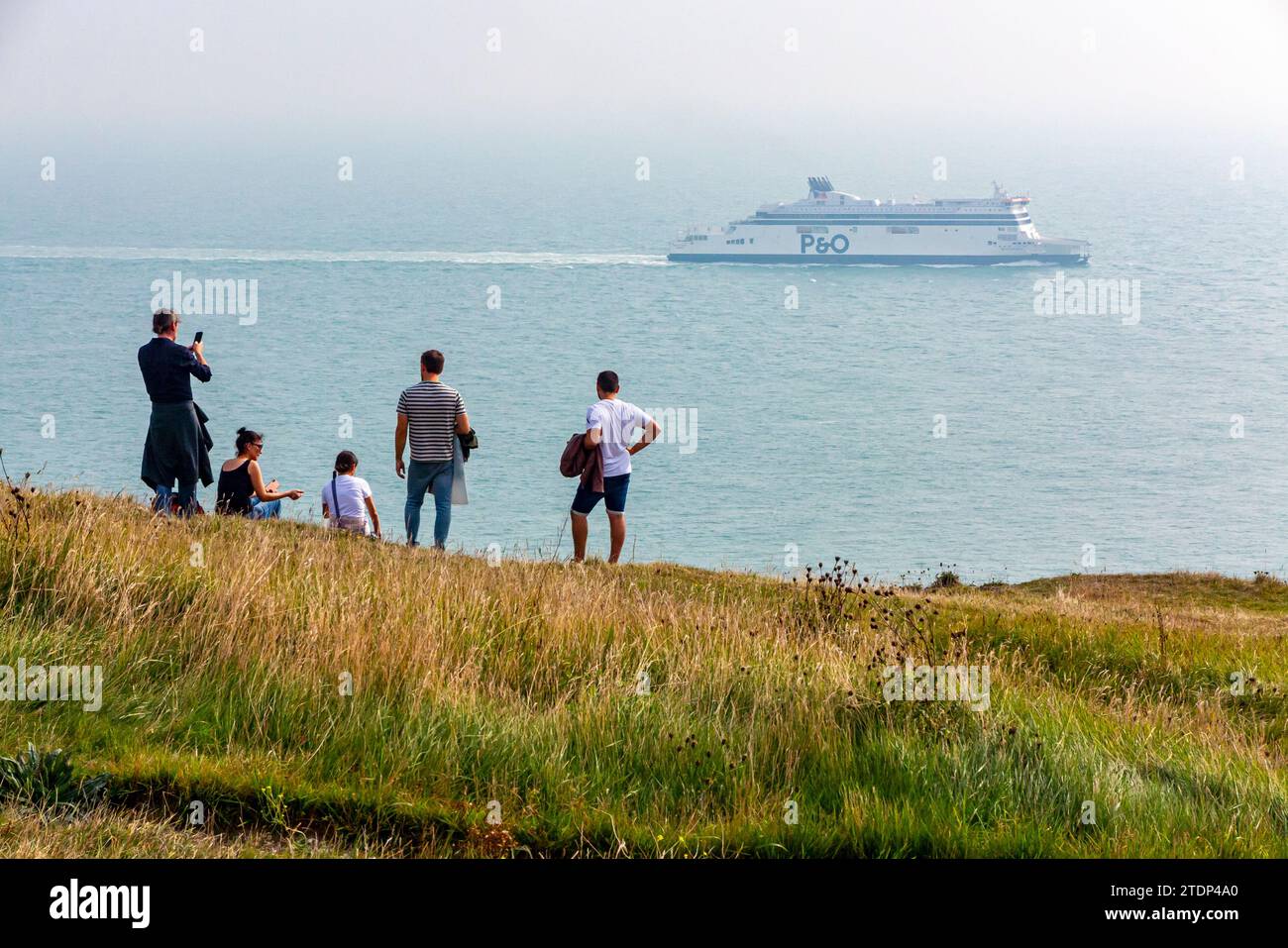 Group of people watching a P&O car ferry cross channel ferry from the White Cliffs of Dover on the Kent coast south east England UK. Stock Photo