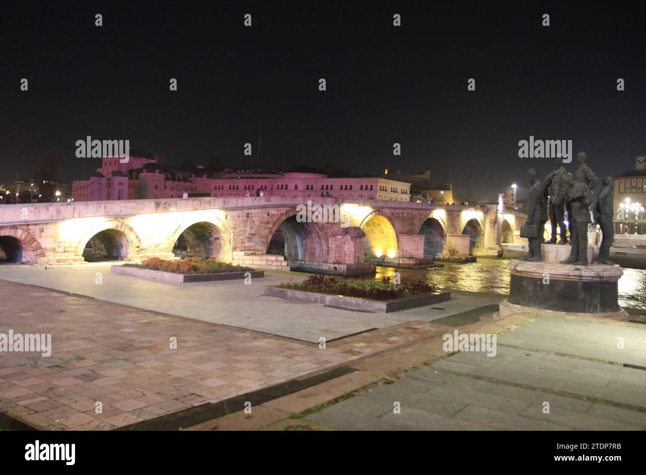 The famous Stone Bridge at nighttime in Skopje, with the Attentators of Solun & Gemidzhii Monument to the right (Boatmen of Thessaloniki). The bridge goes over the Vardar River. Stock Photo