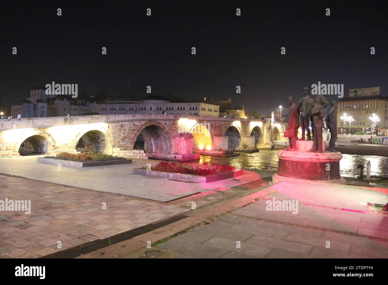 The famous Stone Bridge at nighttime in Skopje, with the Attentators of Solun & Gemidzhii Monument to the right (Boatmen of Thessaloniki). The bridge goes over the Vardar River. Stock Photo