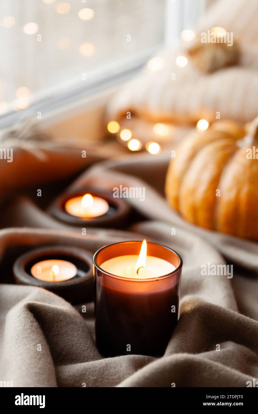 warm cozy window arrangement, winter or autumn concept, candles throw lights Stock Photo