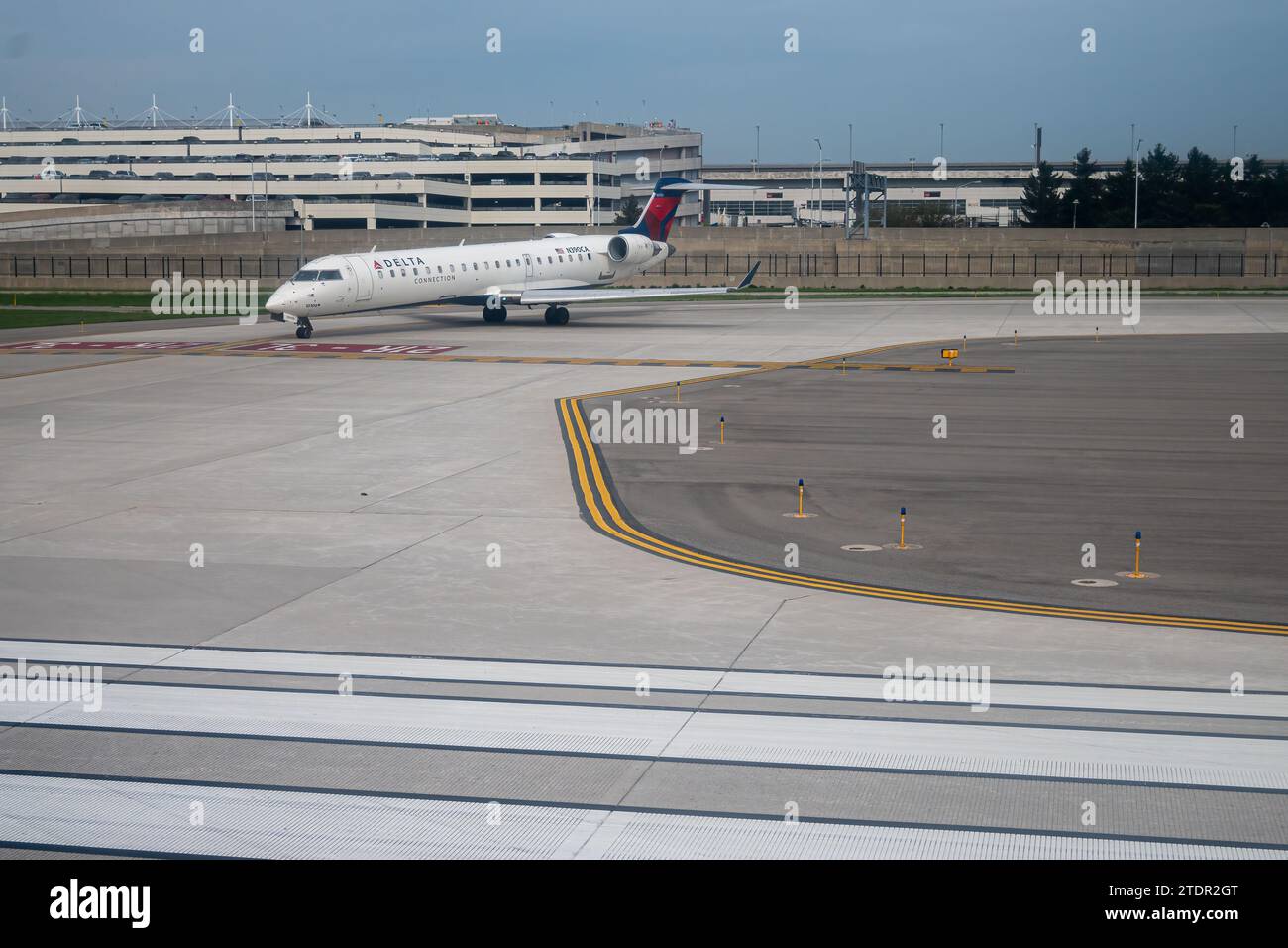 Aircraft N390CA a Mitsubishi CRJ-701ER Passenger jet airliner on the tarmac at  Detroit Metropolitan Wayne County Airport with the parking structure i Stock Photo