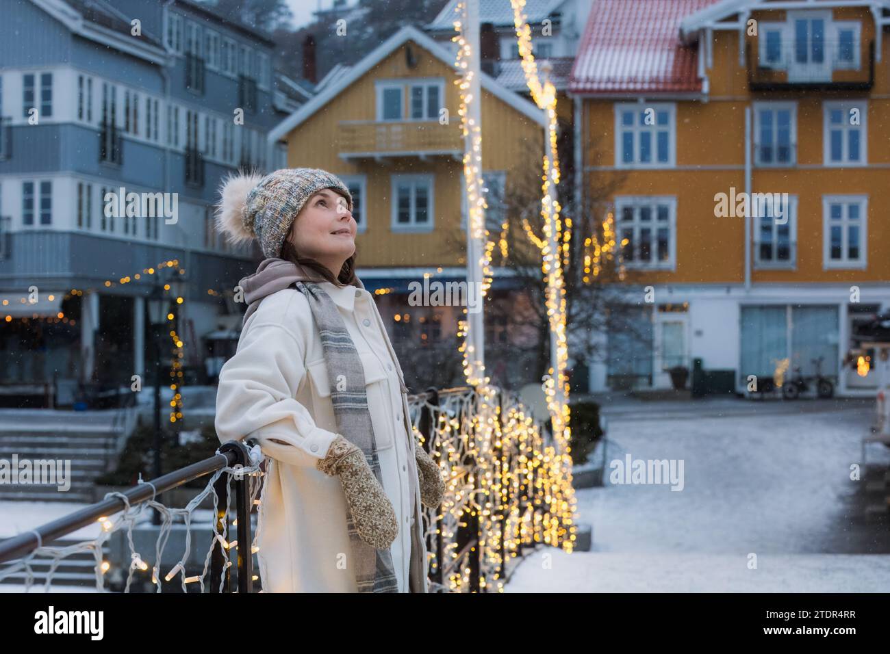 A smiling woman in her prime, enyouing the charm of a Nordic town decorated for Christmas and New year. High quality photo Stock Photo