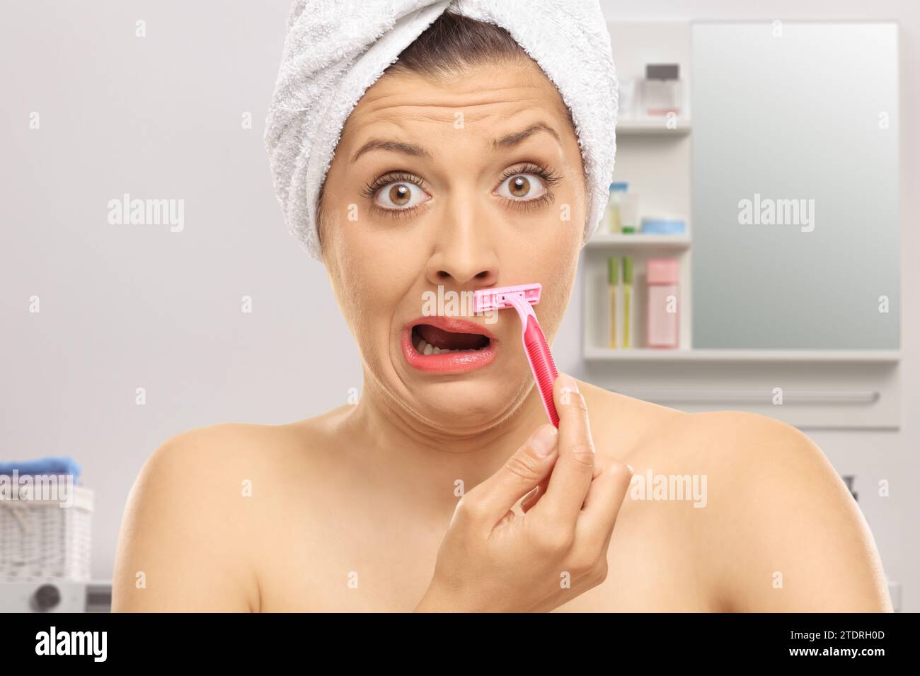 Young woman shaving her moustache with a razor in a bathroom Stock