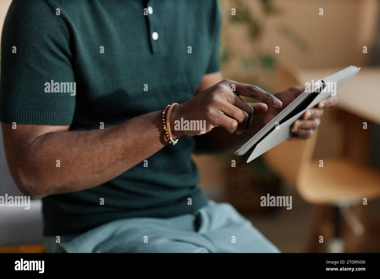 Close up of unrecognizable Black man using tablet at home with hand ...