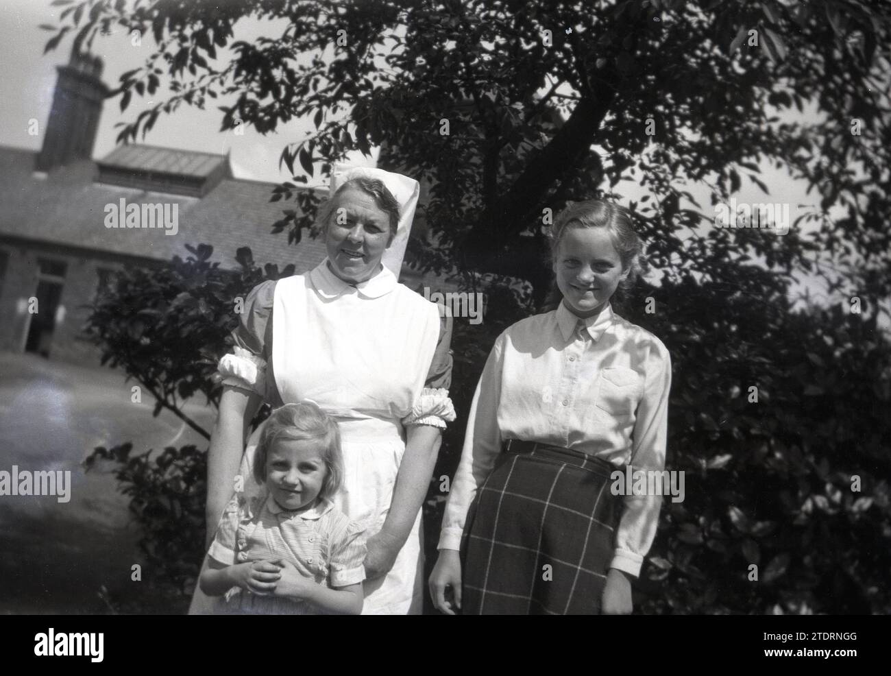 1950s, historical, a nurse with two young children standing for their photo in grounds of a rural hospital, England, UK. Stock Photo