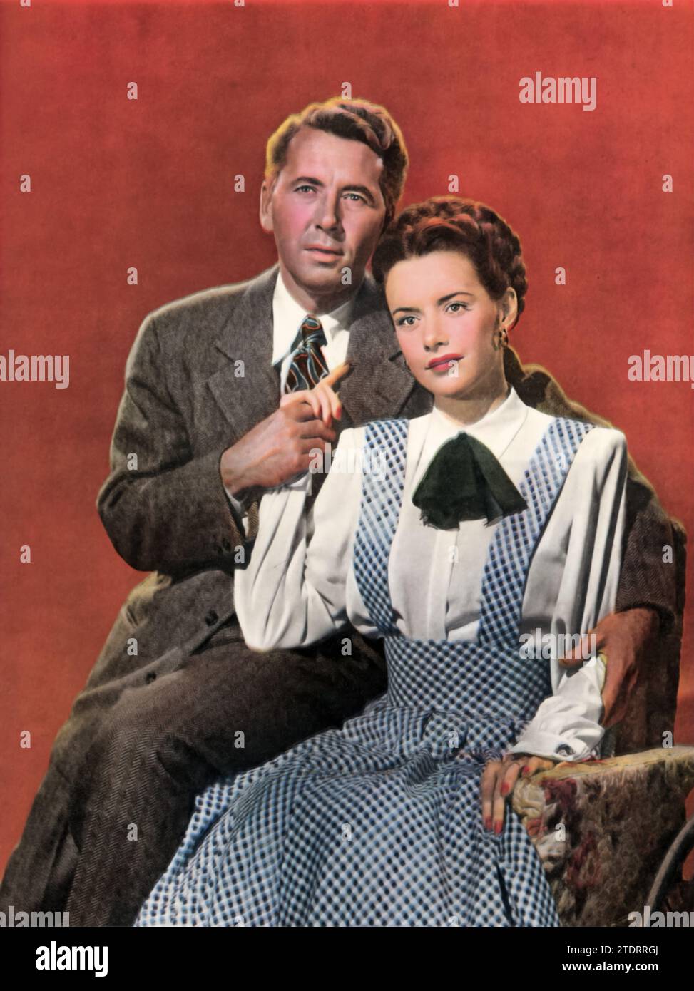 Susan Peters, pictured in a wheelchair beside co-star Alexander Knox on the set of 'Sign of the Ram' (1948), following her severe hunting accident. The film centers around Leah St. Aubyn, played by Peters, a wheelchair-bound matriarch who uses cunning and manipulation to dominate her family, leading to unexpected and dramatic consequences. Peters' portrayal, informed by her personal challenges, adds a gripping and authentic dimension to this family drama. Stock Photo
