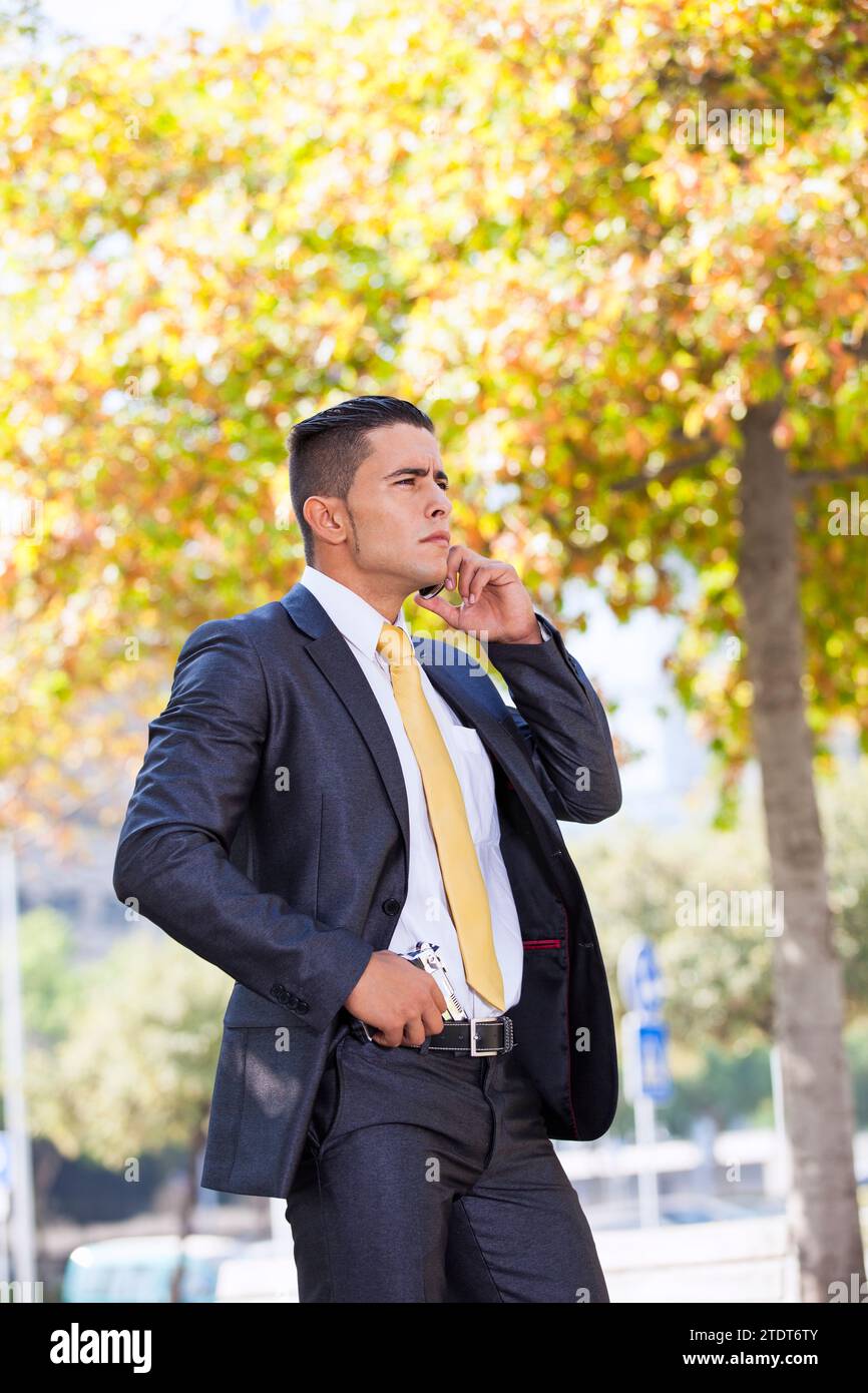 Powerful security businessman talking at his cellphone with a handgun in his belt Stock Photo