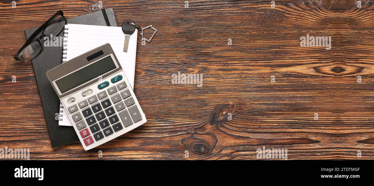 Calculator, notebooks, keys from house and eyeglasses on wooden